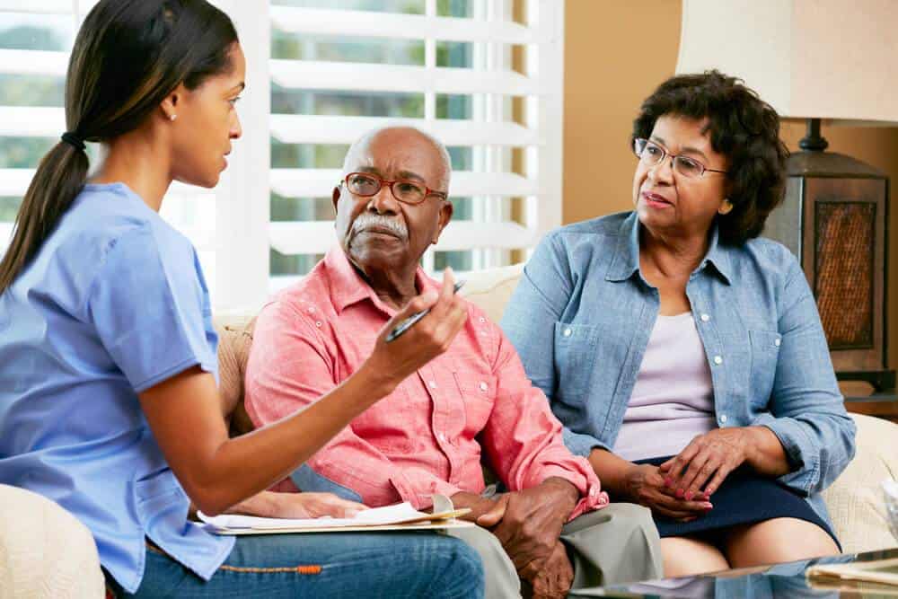 a female caregiver talking to a senior couple