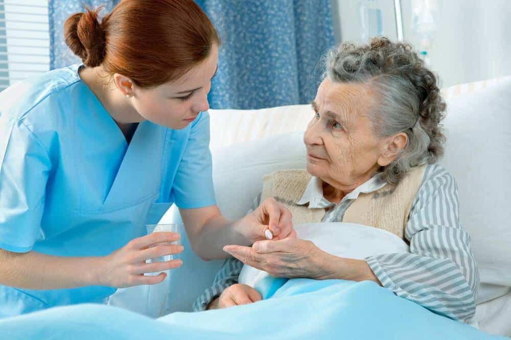 a nurse giving medicine to a senior woman