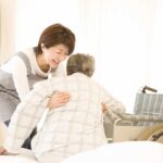 a caregiver helping senior getting out of bed