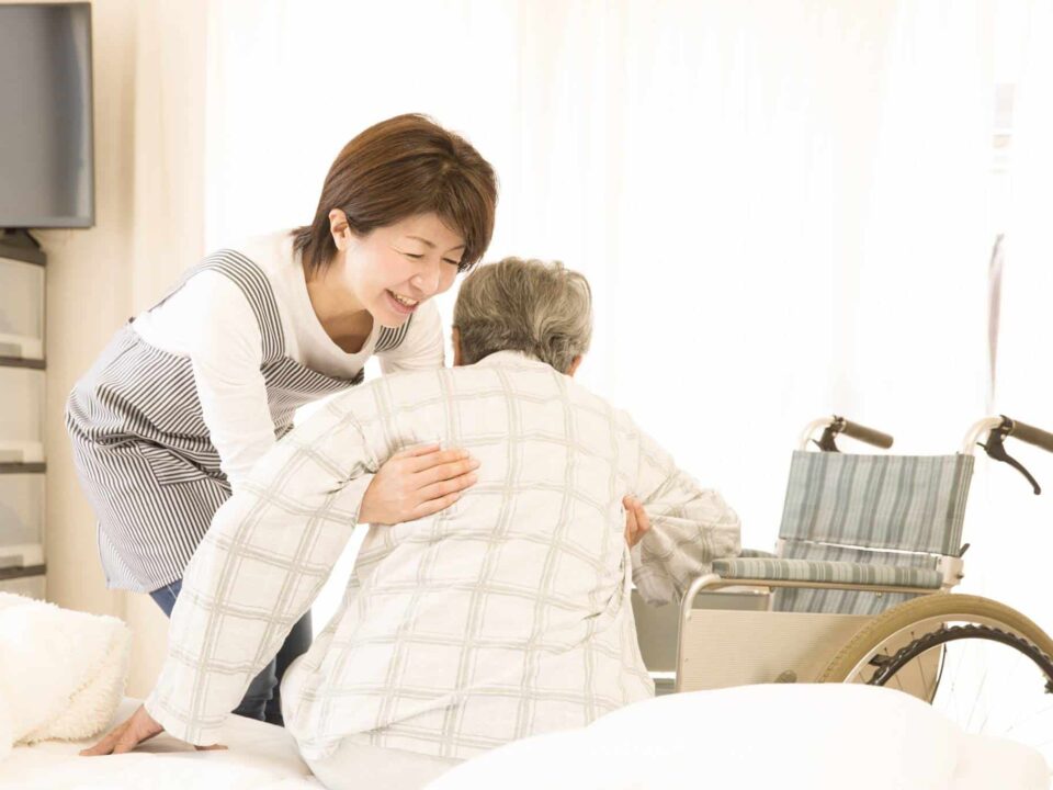 a caregiver helping senior getting out of bed