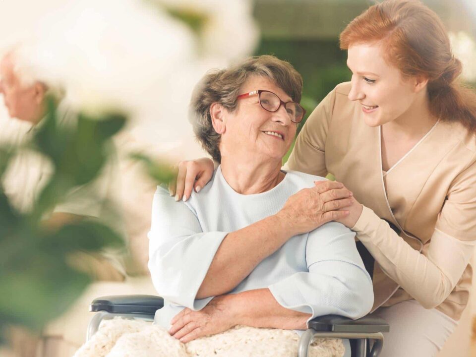 a female caregiver comforting a senior woman sitting on wheelchair
