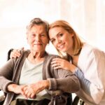 a female caregiver hugging a senior woman on wheelchair