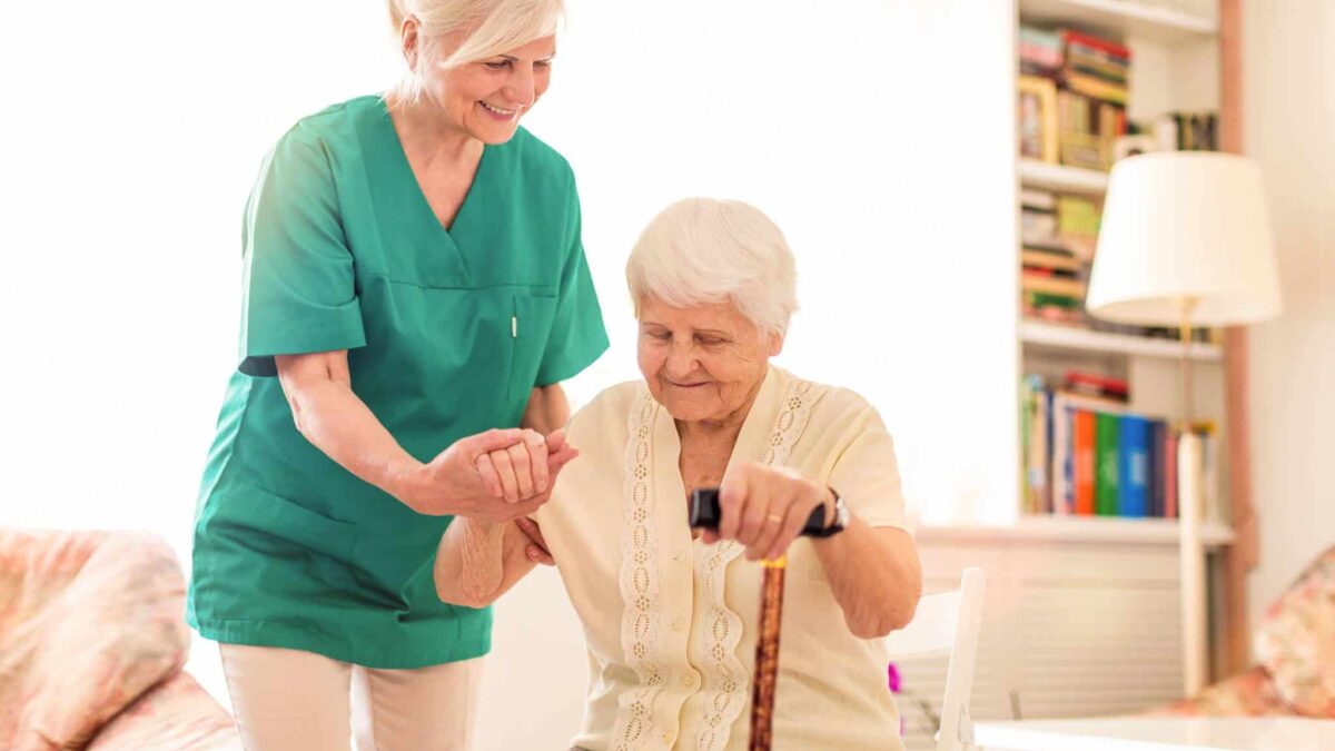 a nurse helping a senior woman stand up