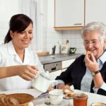 a care giver helping senior woman at breakfast