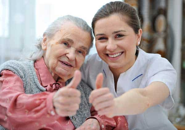 a senio woman and her caregiver showing thumbs up