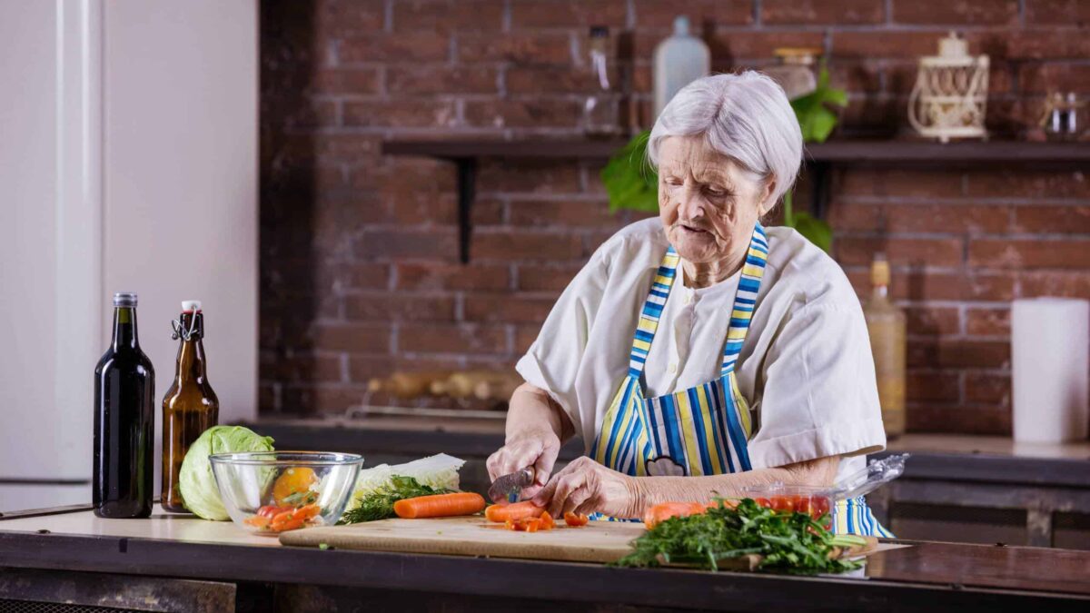 an elderly woman chopping vegetables