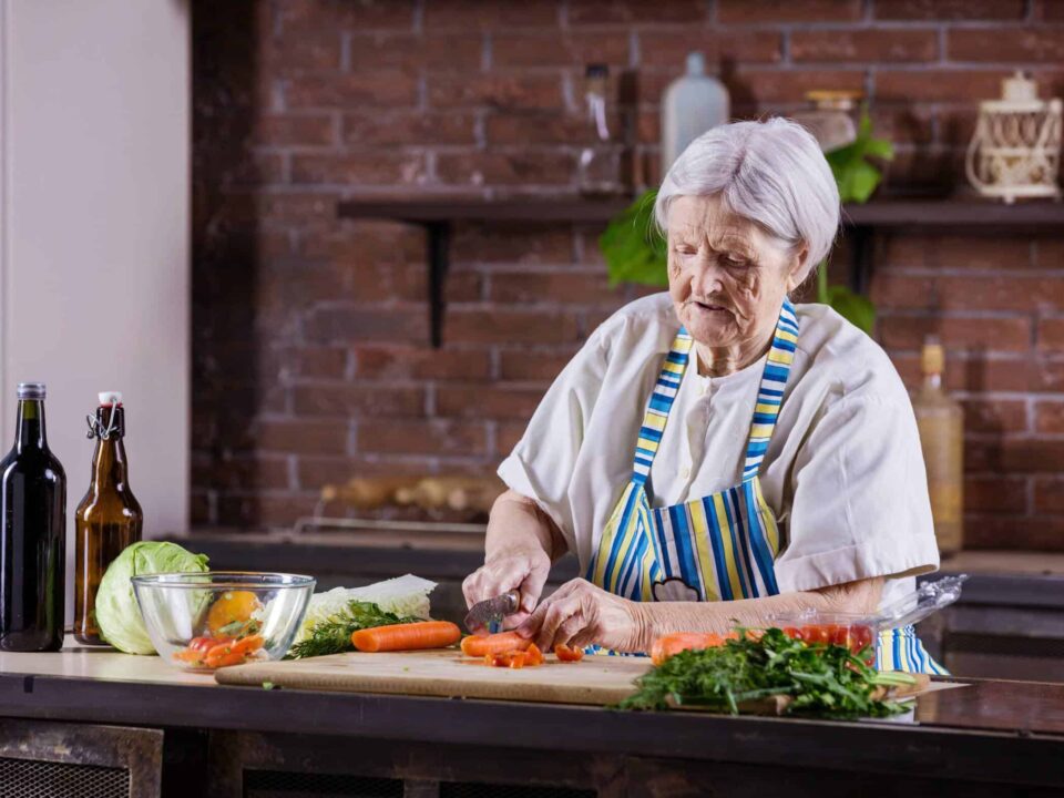 an elderly woman chopping vegetables