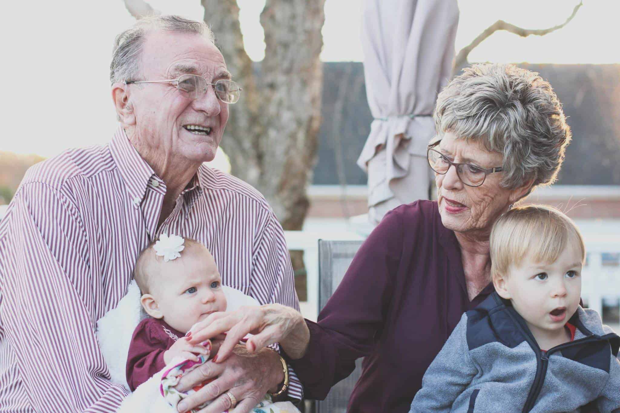 elderly couple holding grandchildren