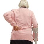 an elderly woman touching her back